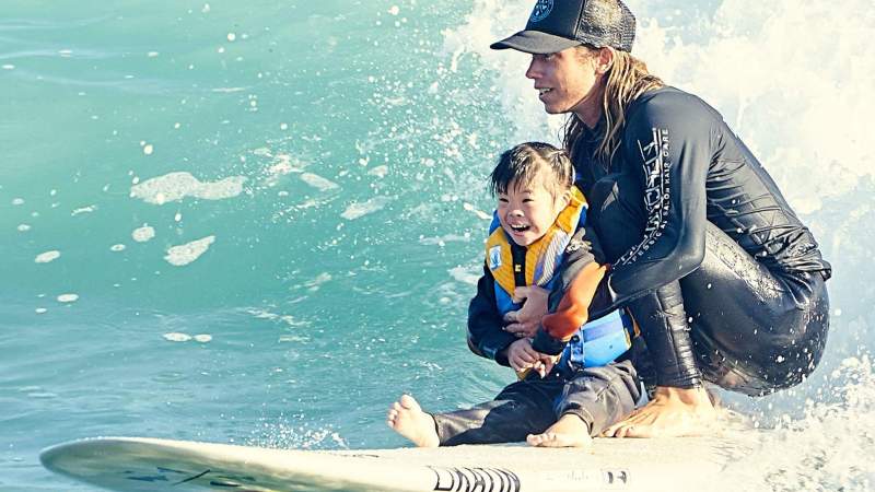 a young girl riding a wave on a surfboard in the water