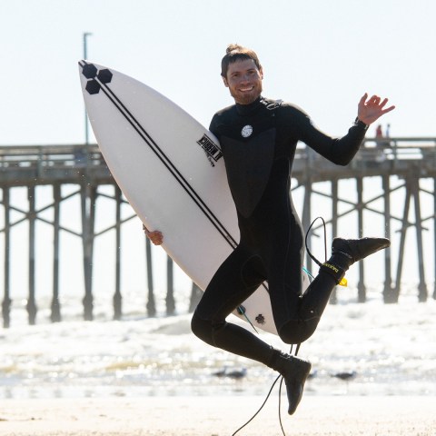 a man in a wet suit carrying a surf board
