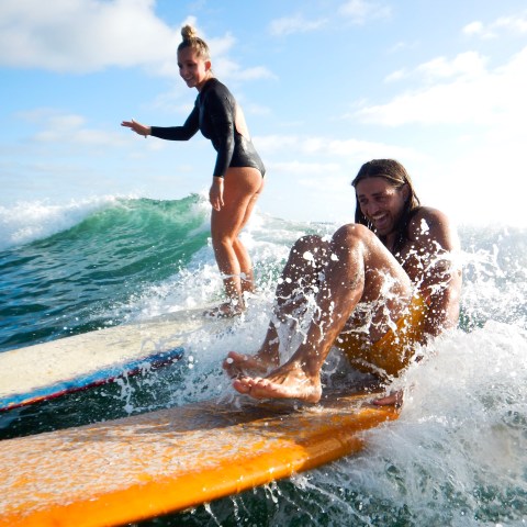 a man and a woman riding a wave on a surfboard in the ocean